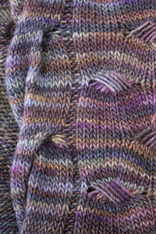 Close up detail of a knitted wrap in shades of purple