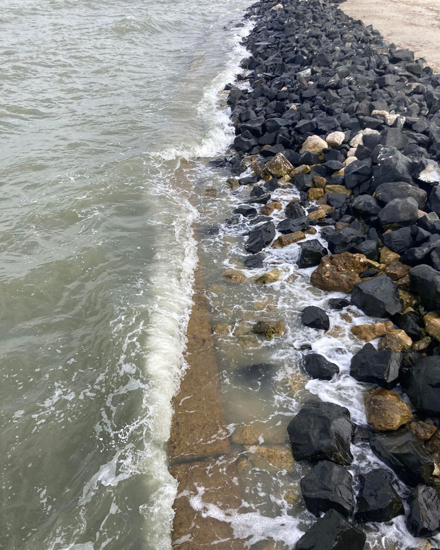 color photograph of  small waves breaking on a rocky shore