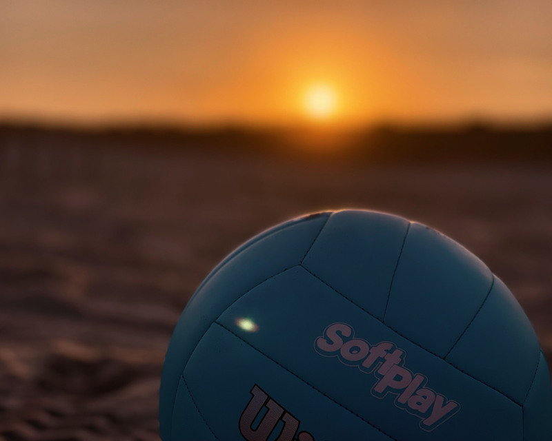 color photograph of a volleyball with the sun setting in the background