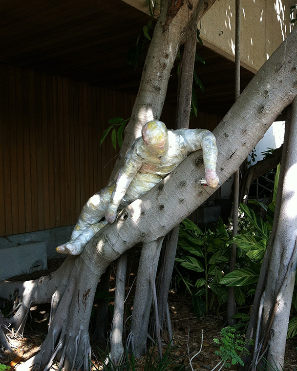 A color photograph of a sculpted figure resting in a Banyan tree 