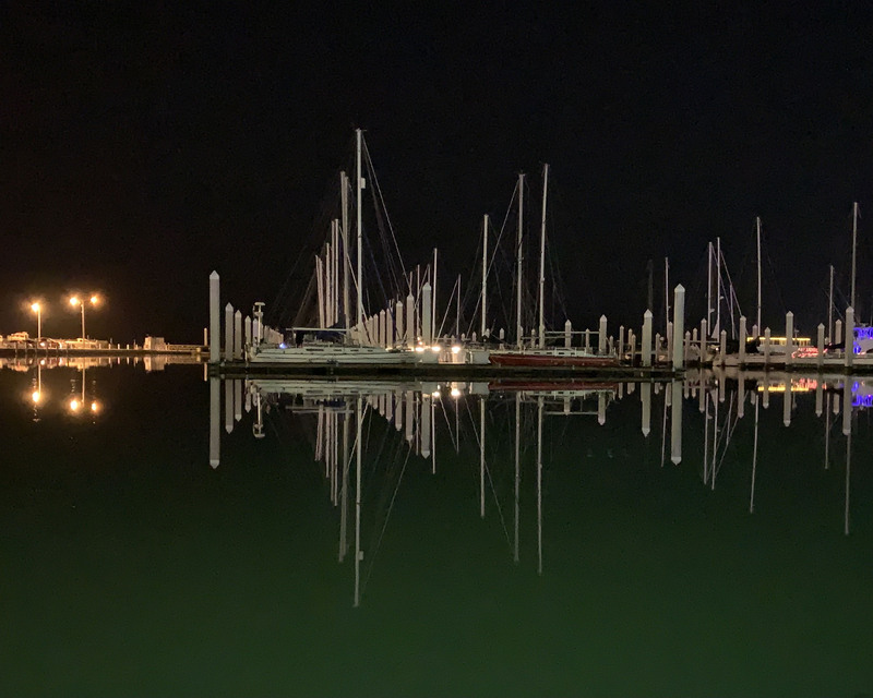 color photograph of a night skyline with boats reflected on the water's surface